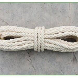 May include: A white cotton rope coiled and tied in the middle. The rope is thick and has a braided texture.