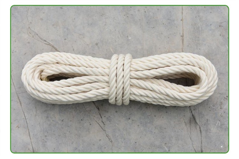 May include: A white cotton rope coiled and tied in the middle. The rope is thick and has a braided texture.