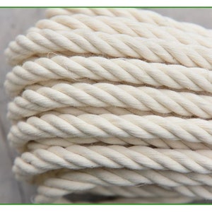 May include: Close-up of a thick, white cotton rope. The rope is twisted and has a natural, rustic look.
