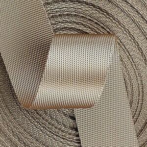 May include: A close-up of a roll of beige webbing with a textured surface. The webbing is woven with a diamond pattern.