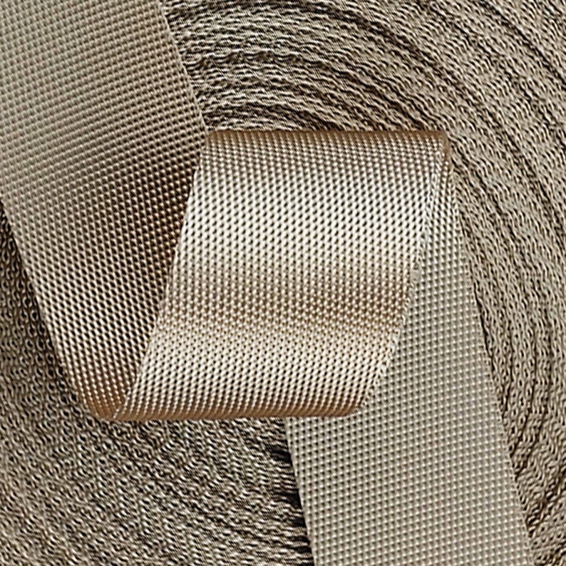 May include: A close-up of a roll of beige webbing with a textured surface. The webbing is woven with a diamond pattern.