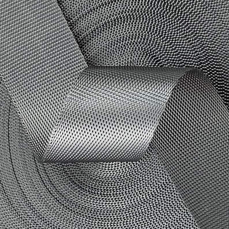 May include: Close-up of a gray woven webbing strap with a textured surface. The strap is folded and layered, creating a pattern of overlapping circles.