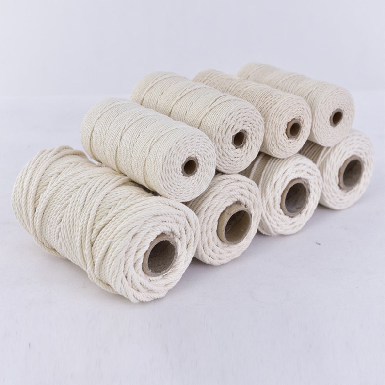 May include: A set of eight spools of natural white cotton rope. The rope is wound tightly around each spool, creating a uniform and neat appearance.