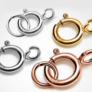 Puede incluir: Cuatro cierres redondos para la elaboración de joyas, en plata, oro y oro rosa. Cada cierre está marcado con "925", lo que indica plata de ley.