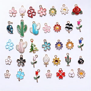 Peut inclure: Assortiment de breloques en émail coloré avec différents motifs, notamment des fleurs, des cactus, un sapin de Noël, une sucette, un trèfle à quatre feuilles et un tournesol.