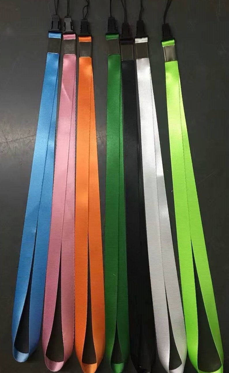 Op de afbeelding: Set van acht kleurrijke lanyards met metalen gespen. De banden zijn in de kleuren blauw, roze, oranje, groen, zwart, wit en limoengroen.