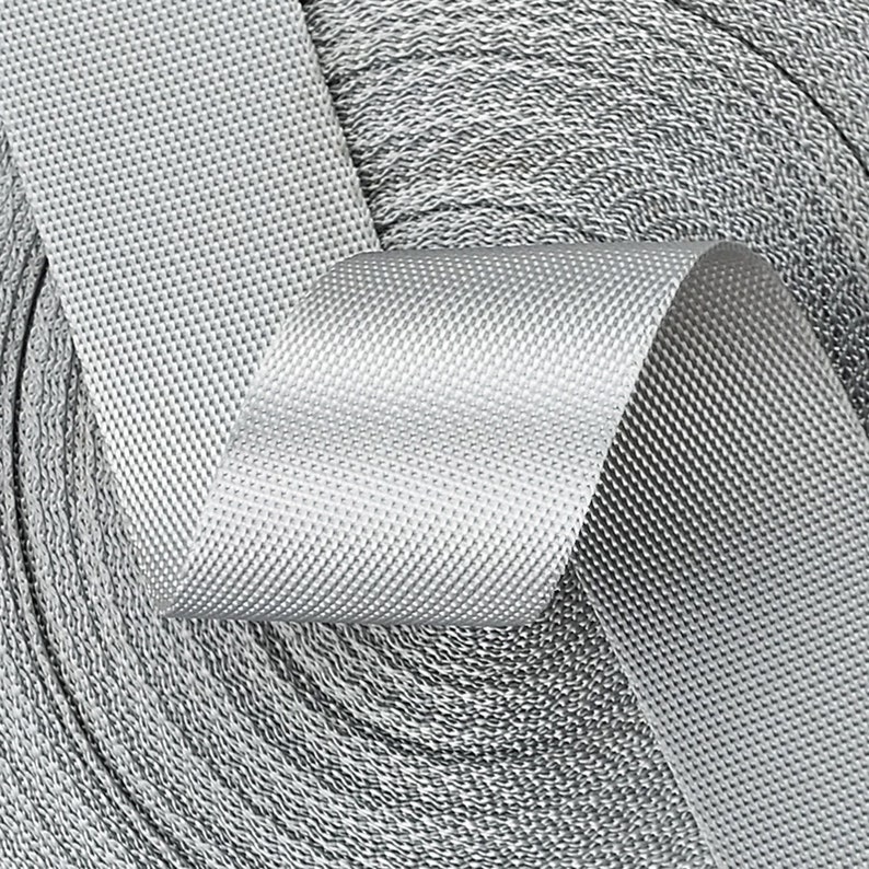 May include: A roll of silver gray webbing with a textured surface. The webbing is rolled up and the end is folded over.