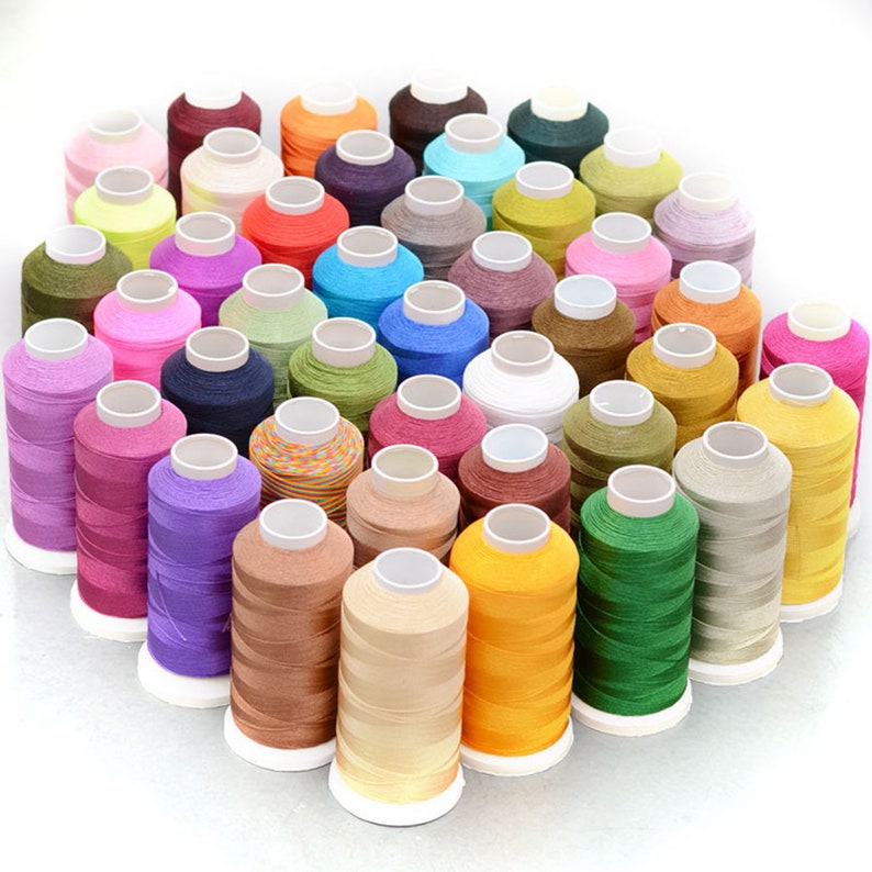 Pode incluir: Uma cole&ccedil;&atilde;o de carret&eacute;is de fio colorido, dispostos em semic&iacute;rculo. Os carret&eacute;is s&atilde;o todos do mesmo tamanho e forma, e s&atilde;o feitos de uma variedade de cores, incluindo vermelho, azul, verde, amarelo e roxo.