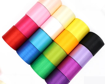 May include: A set of 12 rolls of satin ribbon in various colors, including pink, yellow, green, blue, purple, red, and black. The ribbon is arranged in a pyramid shape.