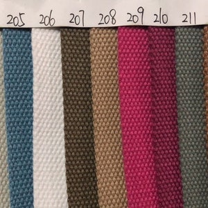 May include: A swatch card with 16 different fabric samples. The samples are arranged in a row from left to right. The colors of the samples are: purple, black, dark gray, light gray, blue, white, brown, beige, pink, dark gray, brown, orange, dark blue, red, and dark blue.