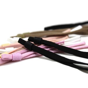 May include: A close-up of a variety of colourful elastic cords with adjustable toggles. The cords are made of a soft, stretchy material and are perfect for crafting or DIY projects.