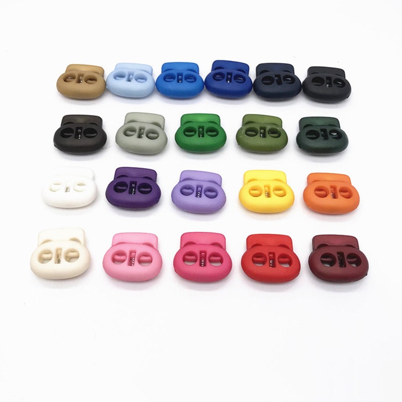 May include: Assortment of 20 plastic toggle clasps in various colors, including brown, blue, green, purple, pink, red, orange, yellow, and white. The clasps are oval-shaped with two holes on each side.