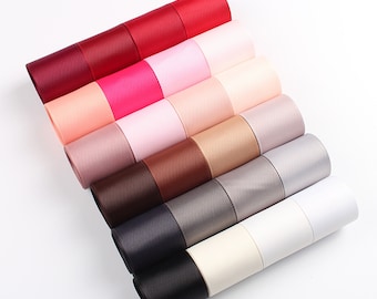 May include: A collection of 12 rolls of satin ribbon in various colors, including red, pink, beige, brown, gray, and white. The ribbon is arranged in a fan shape, with the ends of each roll overlapping.