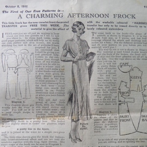 May include: A vintage 1932 sewing pattern page titled A CHARMING AFTERNOON FROCK, featuring a black and white illustration of a person wearing a dress with cape sleeves, a corselet front, and a two-piece skirt, alongside diagrams and instructions.