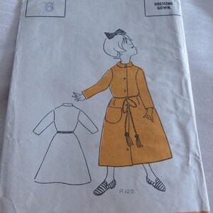 May include: Vintage sewing pattern for a dressing gown, size 6. The illustration shows a mustard-colored coat dress with a belt and pockets. The pattern is from Odhams Press Paper Pattern Service.