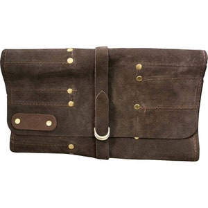 May include: A brown leather tool roll with a strap and buckle closure. The roll has multiple pockets and is secured with brass rivets.