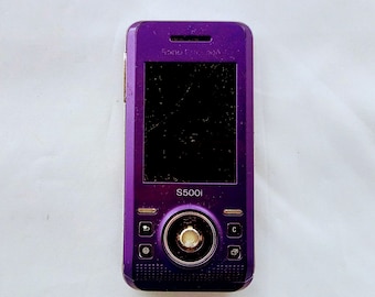 Collectible  Sony Ericsson S500i slider cell phone in metallic purple and silver. Old push-button mobile phone.