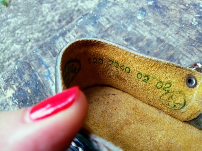 Pode incluir: Close-up do interior de um sapato de couro marrom com uma etiqueta verde que diz "120 7060 02-02".
