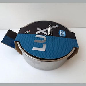 Peut inclure: Une râpe à fromage en acier inoxydable avec une étiquette bleue et blanche qui indique "Lux Grattugia Acciaio Inox" et "Lopardo Inox".