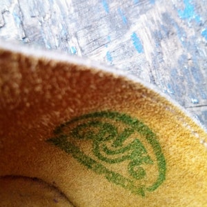 Pode incluir: Close-up do interior de um sapato com um logotipo verde na palmilha. O logotipo &eacute; um design de espiral estilizado.