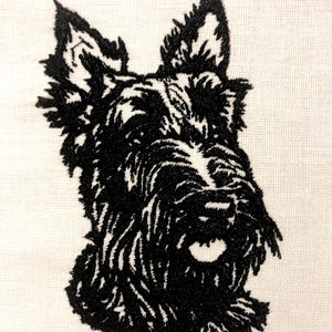 May include: Black and white embroidered image of a Scottish Terrier dog's head.