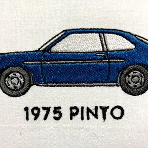May include: A blue 1975 Ford Pinto car, embroidered on a white fabric background.