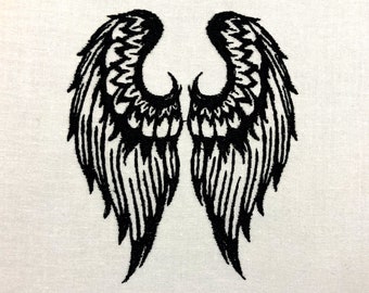 May include: Black embroidered angel wings on a white fabric background.