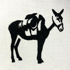 May include: Black embroidered image of a donkey with a saddle on a white background. The donkey is facing right, with its head and ears visible. The saddle is detailed with dark stitching.