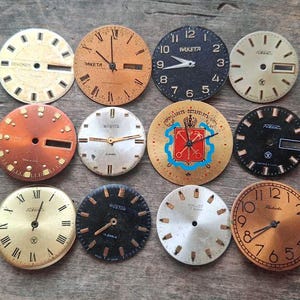 Peut inclure: Une collection de cadrans de montres vintage de différentes couleurs, dont l'or, le noir et l'orange. Certains cadrans présentent des chiffres romains, tandis que d'autres ont des chiffres arabes. Plusieurs cadrans affichent les marques "Raketa" et "Wostok".