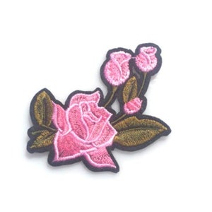 May include: Embroidered rose patch featuring a large open bloom and several buds in varying stages of development. The rose is a vibrant pink with green and gold leaves, outlined with a black border. This patch is suitable for clothing and accessories.