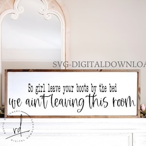 May include: A white wooden sign with a brown frame, featuring the text "So girl leave your boots by the bed we ain't leaving this room".