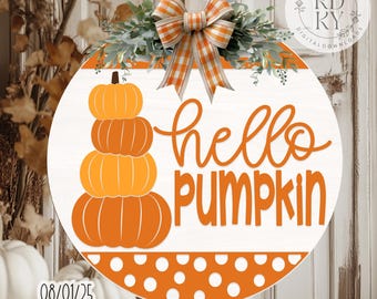 May include: A circular wooden sign with the words "hello PUMPKIN" in orange script. A stack of orange pumpkins is on the left. The sign is decorated with a plaid bow and greenery. The bottom has an orange polka dot design.