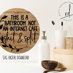 May include: A round wooden sign with a black floral wreath and the text "THIS IS A BATHROOM NOT AN INTERNET CAFE shit & split". The sign is on a white background. SVG-DIGITAL DOWNLOAD is written below the sign.
