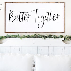 Peut inclure: Une pancarte en bois blanc avec le texte "Better Together" en écriture cursive noire. La pancarte est suspendue au-dessus d'un lit blanc avec une tête de lit blanche et une literie blanche.