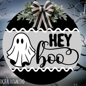 May include: A black and white round door hanger with a gray background. The door hanger has a ghost and the text "Hey Boo" in black.