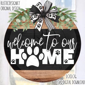 May include: A round wooden sign with the text "welcome to our HOME" in white. The "O" in HOME is a paw print. The sign has a black background and a decorative bow with paw prints. Greenery and a black and white striped bow are at the top.