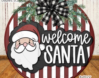Pode incluir: Uma placa redonda com listras verticais bordô e brancas, um laço xadrez preto e branco e ramos de pinheiro verdes. Exibe um rosto de Papai Noel em desenho animado e o texto branco "welcome SANTA" sobre um fundo preto.