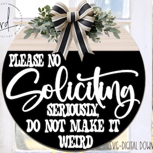 May include: A round wooden sign with a black background and white text that reads "PLEASE NO SOLICITING SERIOUSLY, DO NOT MAKE IT WEIRD". The sign is decorated with a white and black striped bow and greenery.