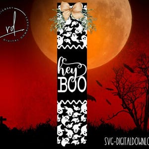 May include: A black and white digital download SVG file for a Halloween door hanger. The design features a black background with white ghosts and the text "Hey Boo" in a white cursive font.