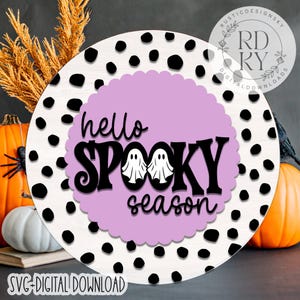 May include: A round, white sign with black polka dots and the text "hello SPOOKY season" in black. The text is on a light purple scalloped circle, with two ghost illustrations. The sign also says "SVG+DIGITAL DOWNLOAD".
