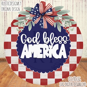 May include: A round wooden sign with a red and white checkered border. The sign features the text "God bless AMERICA" in white, with a blue background. A bow with an American flag design and greenery accents the top.
