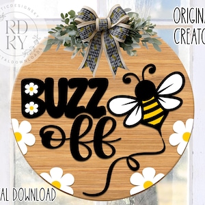 Puede incluir: Un letrero redondo de madera con el texto "Buzz Off" en letras negras. Una abeja de dibujos animados con rayas negras y amarillas se aleja del letrero. El letrero está decorado con margaritas blancas.