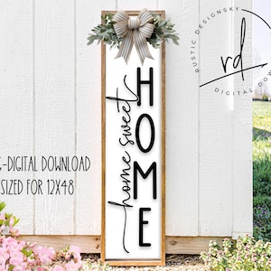 May include: A wooden sign with a white background and black lettering that reads "home sweet home". The sign is decorated with a green wreath and a white bow.