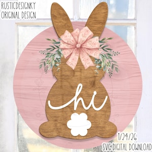 Puede incluir: Colgador de puerta con forma de conejo de madera con un lazo rosa y vegetación. El conejo está sobre un fondo de madera rosa con la palabra "hi" en escritura blanca. El diseño incluye el texto "RUSTICDESIGNKY ORIGINAL DESIGN" y "1/24/26 SVG DIGITAL DOWNLOAD".