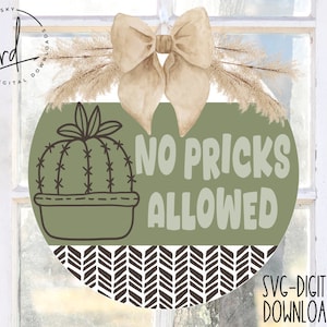May include: A round green and white door hanger with a cactus illustration and the text "No Pricks Allowed". The hanger has a brown chevron pattern at the bottom.