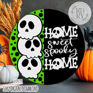 May include: A round Halloween-themed sign with a black and green design. The left side features three white skulls stacked on top of each other. The right side has the words "HOME sweet spooky HOME" in white. The sign also includes the text "SVG DIGITAL DOWNLOAD".