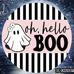 Puede incluir: Un círculo de rayas negras y rosas con un fantasma blanco que lleva una corona de flores y el texto "oh, hello BOO" en negro.