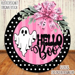 以下が含まれることがあります： ピンクと黒のストライプの背景に、白い幽霊と黒い文字で「HELLO BOO」と書かれた円形の看板。縁は黒地に白の水玉模様。上部にはクモの巣とコウモリの模様が入ったピンクのリボンと緑の葉があしらわれています。