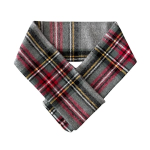 May include: A gray plaid scarf with red, yellow, and white accents. The scarf is folded in a V-shape, showcasing the intricate pattern. The fabric appears to be a soft, woven material, suitable for cooler weather. The scarf is a classic accessory.