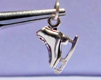 Peut inclure: Breloque en argent en forme de patins à glace. Le breloque est attaché à un anneau de saut en argent.